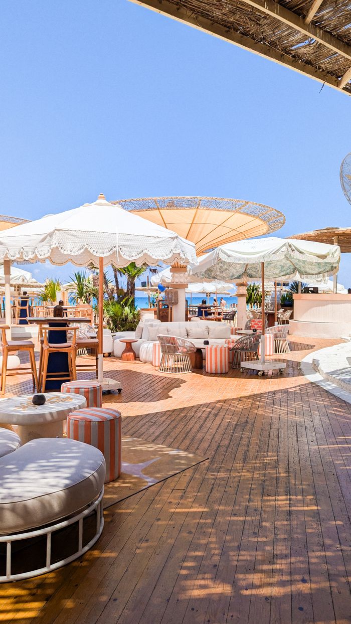 Sunny outdoor beachfront resort patio with umbrellas and seating, perfect for relaxation and leisure.